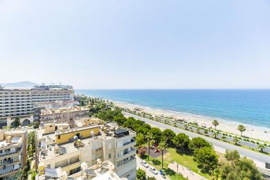 Alanya ejendomsvisning med udsigt over Middelhavet, stranden og bybilledet under en klar, blå himmel.