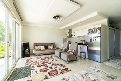 Jasny apartament w Alanyi z salonem, otwartą kuchnią, kafelkami na podłodze i dużymi oknami zapewniającymi naturalne światło.