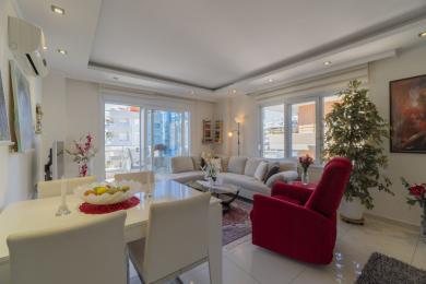 Lichte woonkamer in een appartement in Alanya met witte tegelvloeren, moderne meubels en toegang tot het balkon.