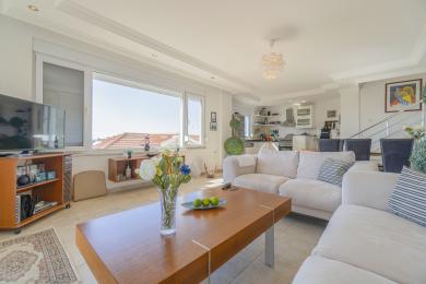 Salon lumineux et ouvert d'Alanya avec des canapés blancs, des accents de bois et une vue sur la ville.