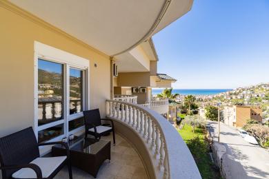 Alanya'da hasır mobilyalar, mermer korkuluk ve parlak güneş ışığında muhteşem deniz manzarası olan balkon.