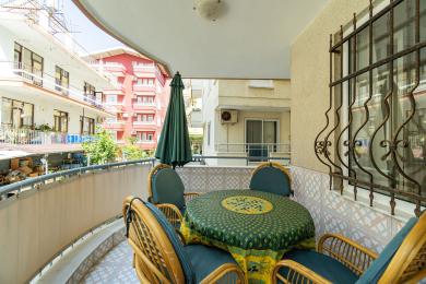 Alanya əmlakında ratan mebel, naxışlı süfrə və parlaq gün işığı olan balkon, rahat bir açıq havada yemək sahəsi yaradır.