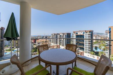 Alanya woning balkon met wicker meubilair biedt helder, zonnig uitzicht op de stad en een ontspannen sfeer.