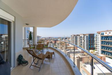 Alanya woning balkon met wicker meubilair, tegelvloeren en panoramisch uitzicht op de stad en de zee.
