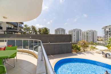 Varanda de propriedade em Alanya com vista para a piscina, com luz natural brilhante, grades modernas e assentos ao ar livre.