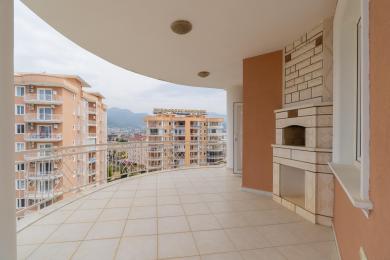 Alanya-Immobilienbalkon mit Fliesenboden, Außenkamin und malerischem Blick auf die Stadt und die Berge.