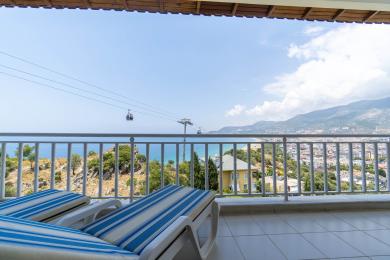Balkon nekretnine u Alanji sa ležaljkama nudi zadivljujući pogled na Sredozemno more i žičaru.