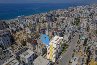 Luftaufnahme einer Immobilie in Alanya, die die Lage des Gebäudes in der Nähe des Strandes und des Stadtzentrums zeigt.