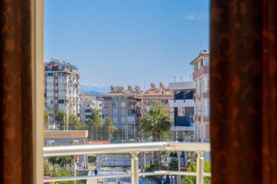 Pogled s balkona na grad Alanya s modernim zgradama i udaljenim planinama.