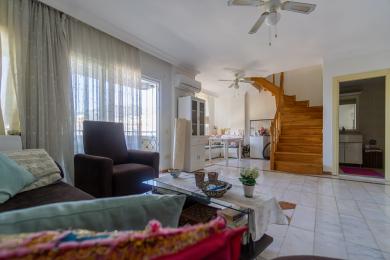 Living spațios în Alanya cu podele de marmură, scară din lemn, scaune confortabile și lumină naturală de la ușile balconului.