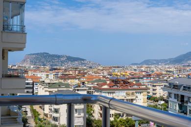Balcon avec vue panoramique sur la ville d'Alanya et la montagne, atmosphère lumineuse et ensoleillée.