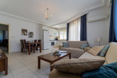 Ljust Alanya vardagsrum med matplats, modernt kök och bekväm sittgrupp.