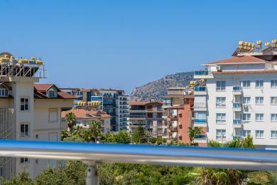 O vedere de pe balcon a apartamentelor din Alanya sub cer senin, cu vegetație luxuriantă.