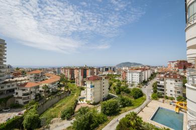 Balkón s výhledem na nemovitost v Alanyi s panoramatem města, Středozemním mořem a jasnou, slunnou atmosférou.