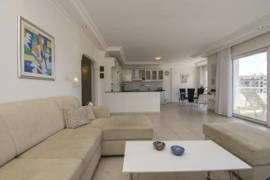 Alanya mulki: Ochiq rejadagi yorug' yashash xonasi oshxona, ovqatlanish joyi, balkon chiqishi va neytral, qulay mebellar bilan.