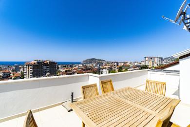 Vista da varanda do apartamento de Alanya, mostrando vistas da cidade, do mar e da montanha, perfeita para refeições ao ar livre.