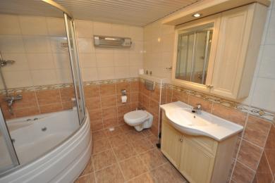 Baie într-o proprietate din Alanya, cu jacuzzi, pereți cu gresie și un dulap de toaletă din lemn deschis cu spațiu de depozitare.