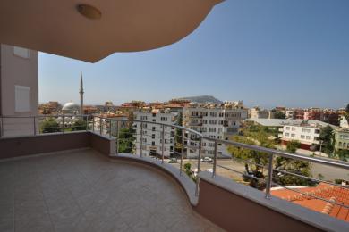 Alanya ejendom altan med flisegulv, rustfri stål gelændere og en lys, solrig udsigt over byen.
