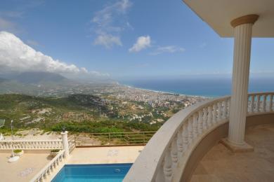Balkon nekretnine u Alanji sa kamenom balustradom, bazenom i panoramskim pogledom na obalu pod vedrim nebom.