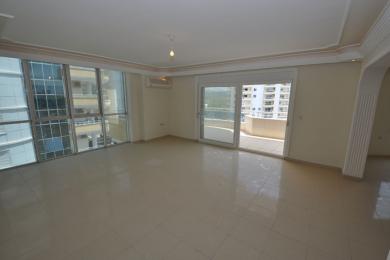 Helles Wohnzimmer in Alanya mit Fliesenböden, großen Fenstern, Zugang zum Balkon und neutralen Tönen, die eine geräumige Atmosphäre schaffen.