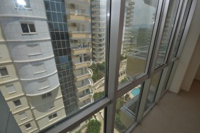 Valoisa Alanyan kiinteistön aurinkohuone, jossa on lattiasta kattoon ulottuvat ikkunat ja upeat näkymät ympäröiviin rakennuksiin ja maisemaan.