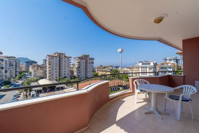 Balcone soleggiato ad Alanya con tavolo e sedie bianche, che offre viste sulla città.