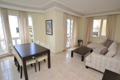 Alanya property living room featuring a dark wood table, neutral sofa, tile floor, and a bright, airy atmosphere.