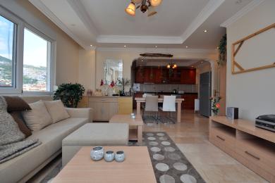 Propriété à Alanya avec un salon décloisonné avec des sols en marbre, une cuisine moderne et une atmosphère lumineuse et aérée.