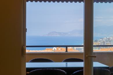 Alanya'daki balkon manzarası cam masa, hasır sandalyeler ve çarpıcı sahil manzarası sunmaktadır.