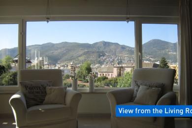 Bright Alanya living room features comfortable armchairs and a panoramic window view of the mountains.