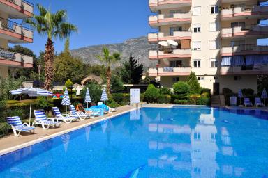 Alanya dovolenkové domy: Relax pri bazéne v slnečnom apartmánovom komplexe s výhľadom na hory.