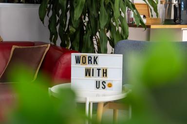Современное офисное помещение в Алании с вывеской "Work With Us", приглашающей к сотрудничеству и росту.